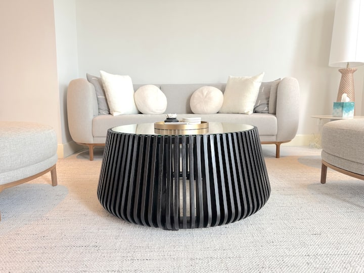 Sala de estar con cómodos asientos para 5 personas, difusor de aceite esencial y posavasos de mármol.