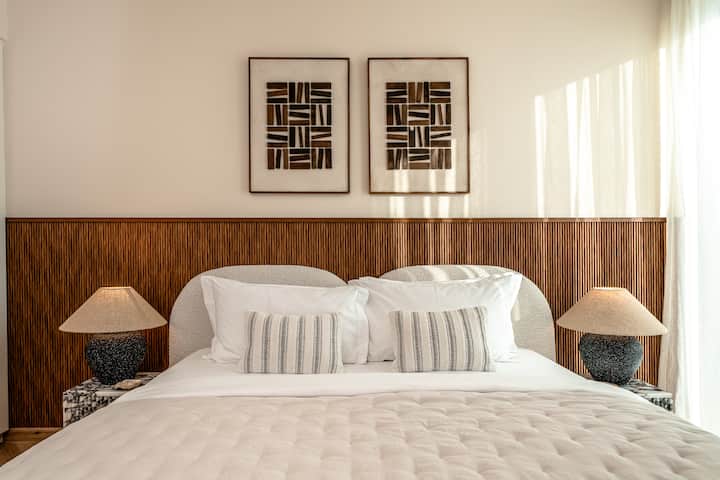 Habitaciones elegantes con ropa de cama lujosa, decoración moderna y abundante luz natural a través de grandes ventanales.