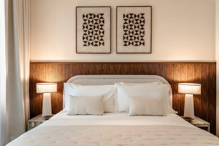 Habitaciones elegantes con ropa de cama lujosa, decoración moderna y abundante luz natural a través de grandes ventanales.