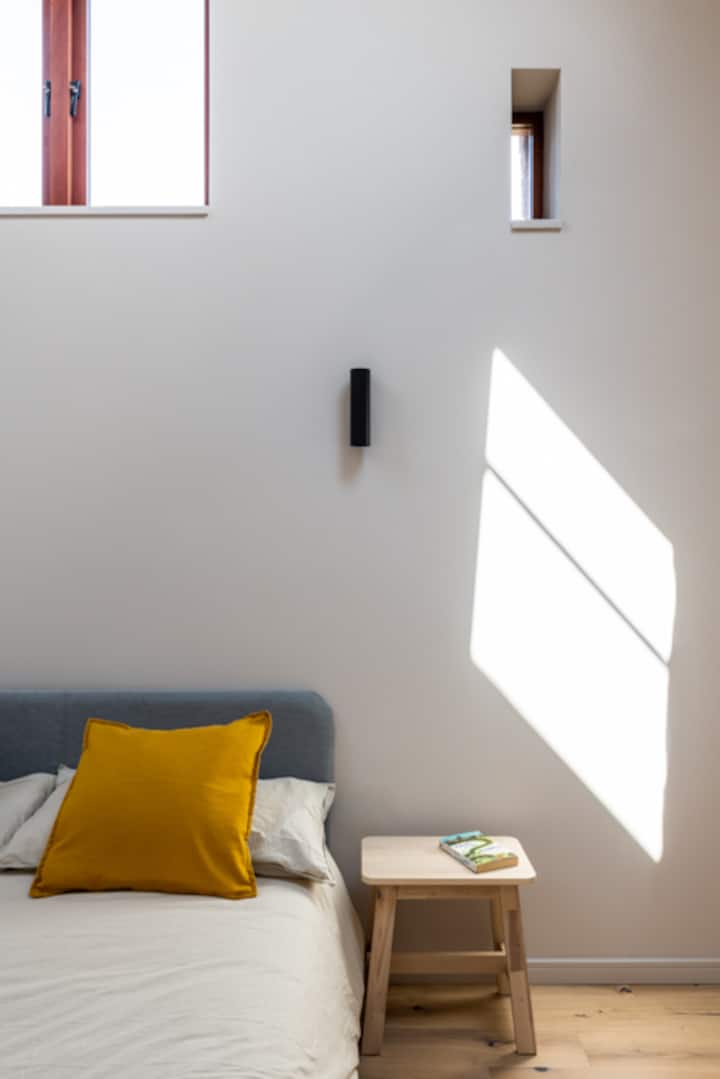 Dormitorio principal con techo abovedado de doble altura y vigas