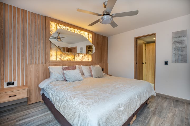 בחדר השינה השקט הזה יש מיטה זוגית גדולה, עיצוב מואר, מאוורר תקרה ונגיעות מינימליסטיות לשינה רגועה.