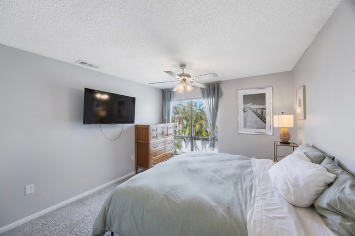 Spavaća soba s bračnim krevetom, pametnim televizorom, djelomičnim pogledom na vodu i zavjesama koje zatamnjuju prostoriju