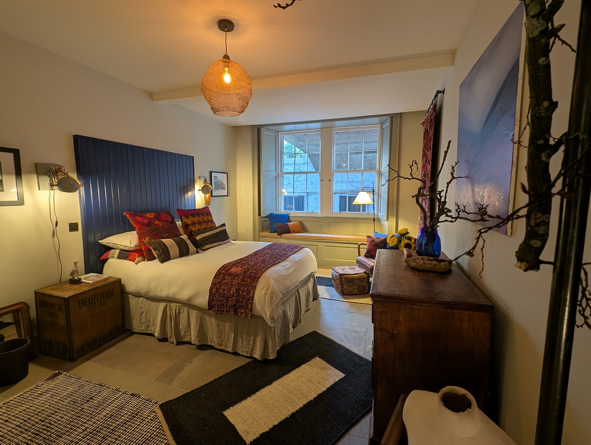 Chambre éclectique avec lit king size et grand siège de fenêtre orienté vers le sud. La chambre « T's Room » est dotée de beaucoup d'espace de rangement, d'un coin lecture pour parcourir la littérature écossaise et d'un miroir de barbier vintage. La salle de bain attenante est équipée d'une douche à effet pluie.