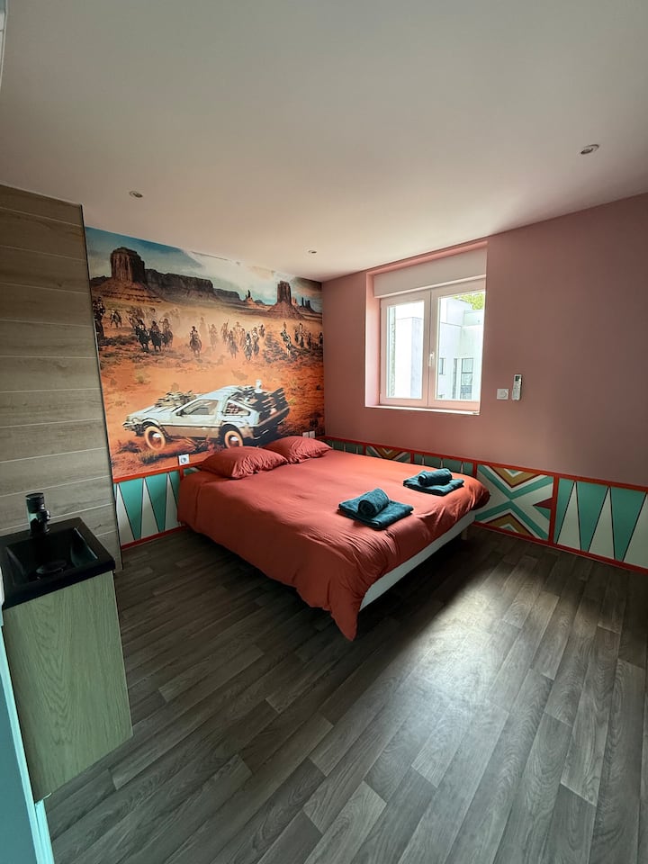 Chumba cha kukaribisha chenye kitanda cha watu wawili na mapambo ya ukutani ya kimaridadi, kwa ajili ya mapumziko ya amani katika mazingira ya starehe