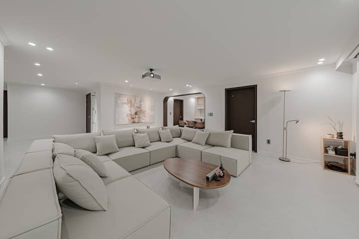 이 넓은 거실에는 대형 섹셔널 소파가 있어 단체로 휴식을 취하기에 안성맞춤입니다. 천장 프로젝터와 현대적인 인테리어가 세련되고 편안한 엔터테인먼트 공간을 제공합니다.