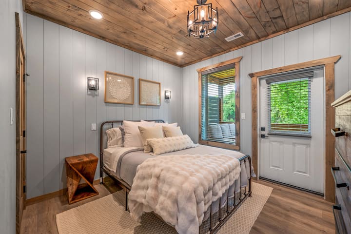 A cozy bedroom with wood-paneled walls, plush bedding, and soft lighting.