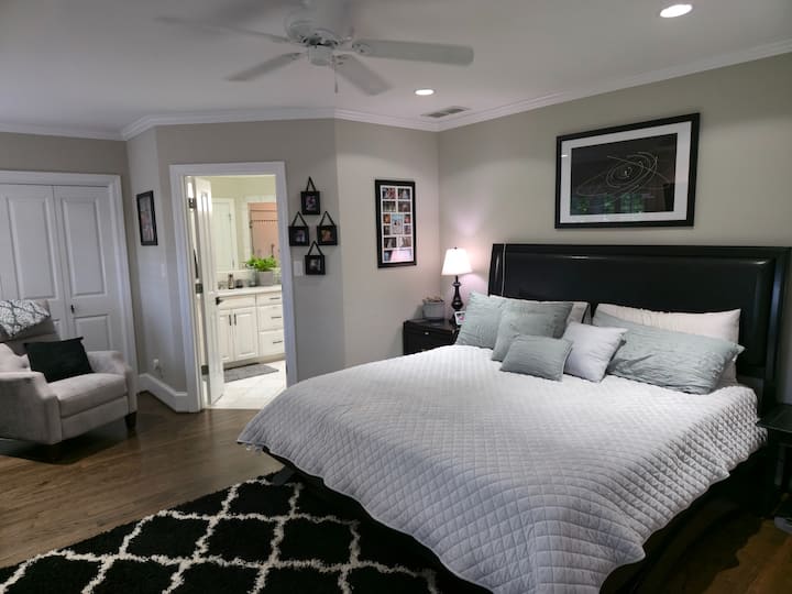Suite principale moderne et confortable avec un lit king size, une télévision intelligente de 60 pouces, un coin salon, un grand placard et des stores occultants automatiques pour une nuit de sommeil parfaite ou un moment de détente en tout confort et en toute intimité.