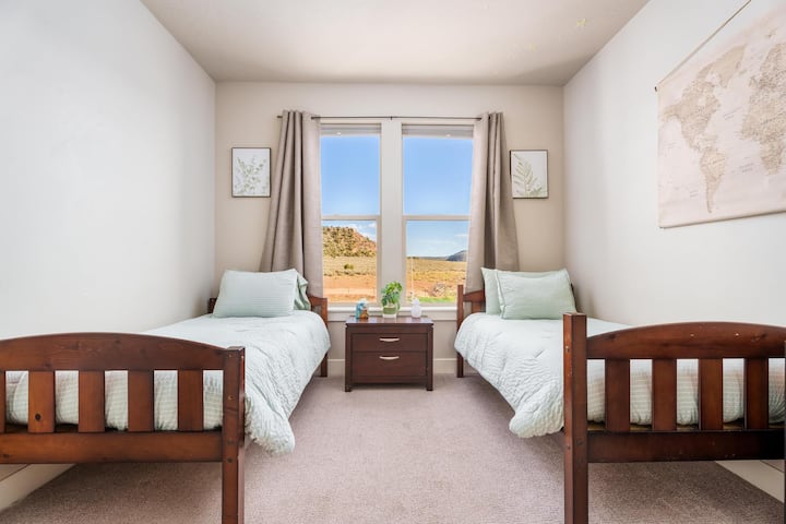 Habitación acogedora con dos camas individuales, cortinas opacas y un vestidor con tocador incorporado. Disfruta de unas vistas impresionantes a la montaña desde la ventana. Baño compartido Jack y Jill con tu propio inodoro, ducha y bañera privados para mayor comodidad y privacidad.