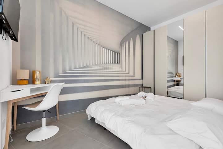 Acogedor salón con un sofá cama abierto y una pared decorativa de alto impacto que da profundidad y estilo al entorno. El espacio es espacioso y está bien organizado, con acceso a un balcón con vistas a la ciudad.