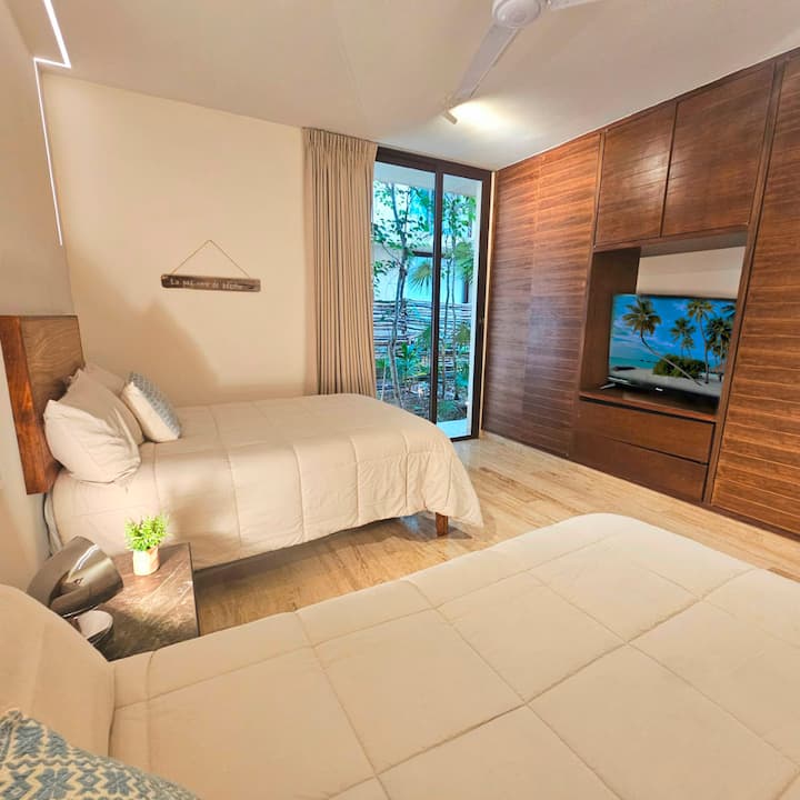 Bedroom for 4 guests with air conditioning, TV, private bathroom, and beautiful views of a tropical garden. Ideal for relaxing and enjoying the nature of Tulum in a comfortable and quiet environment.