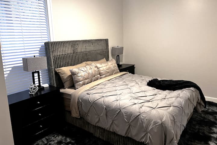 Quarto espaçoso com cama queen size, duas grandes mesas de cabeceira com três gavetas, tomadas de mesa/estações de carregamento, tapete de pelúcia super macio, lâmpadas touch lite, ventilador de teto remoto e armários duplos