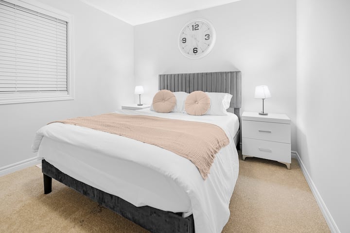 Светла спална соба со плишан кревет, едноставен декор и смирувачки тонови за мирни ноќи.