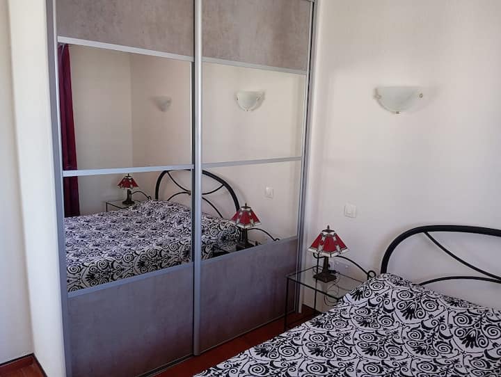 Habitación con cama de matrimonio, armario de pared, armario de esquina, dos mesitas de noche con lámparas Tiffany.