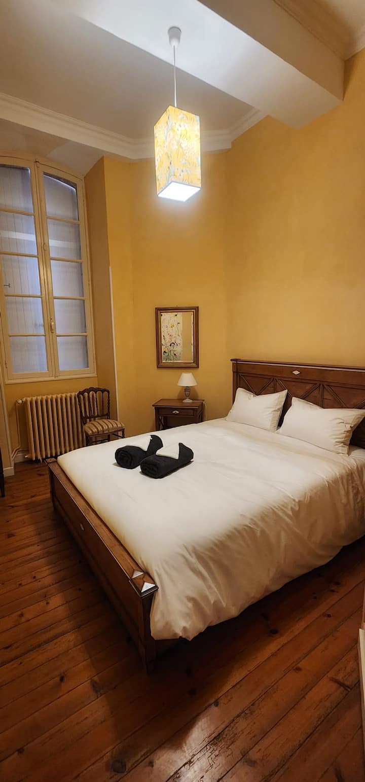 Haut Plafond, parquet, table de chevet avec deux lampes. Petite commode, miroir, chaise et tableau.

Dari kubwa, parquet, meza kando ya kitanda yenye taa mbili. Kifaa kidogo cha kujipambia, kioo, kiti na uchoraji.