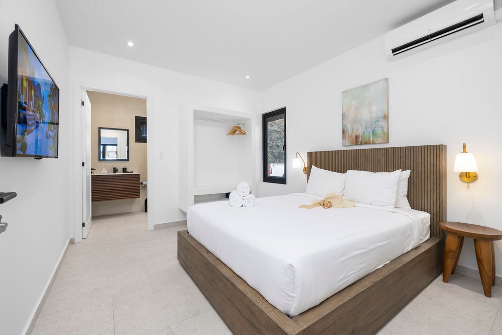 חדר שינה מואר ושלו עם חדר רחצה צמוד, מיזוג אוויר, טלוויזיה חכמה ומיטה נוחה לשהייה רגועה.