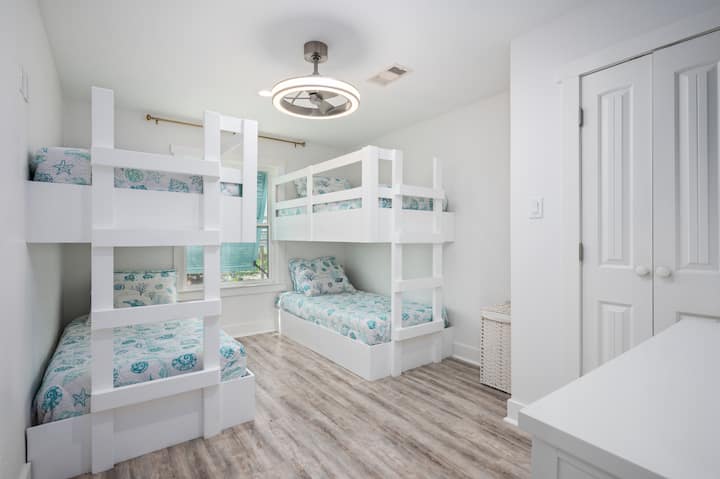 - Соба на спрат погодна за деца со две двокреветни легла и постелнина на плажа
- Белите вградени влошки и разиграните листови за океански печатење додаваат шарм на светлиот простор
- Совршено за преспивање или братучеди кои споделуваат забавно сеќавање за одмор заедно