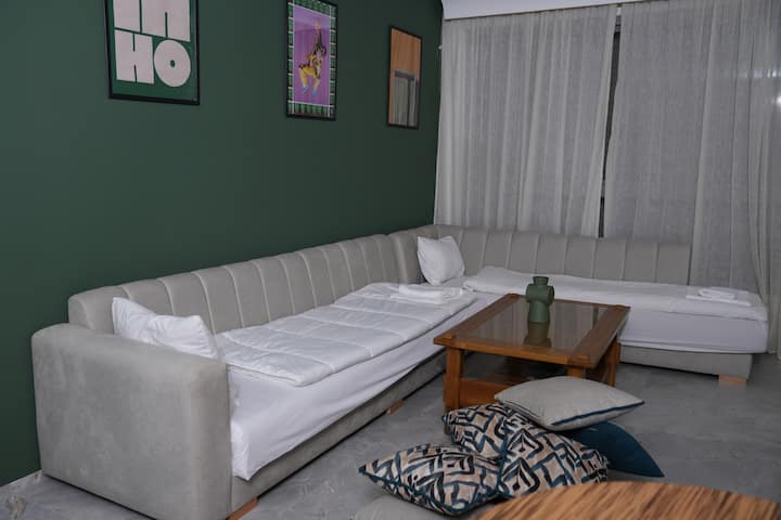 ห้องนั่งเล่นที่อบอุ่นพร้อมโซฟาทรงตัวแอลและผนังสีเขียวสไตล์โมเดิร์น