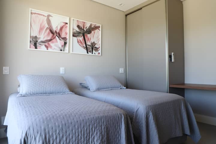 Quarto com com duas camas de solteiro e uma cama auxiliar.