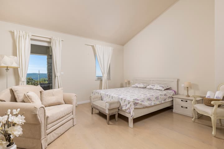 Dormitorio acogedor y espacioso con una cama tamaño king y un sillón extraíble, ideal para familias con un niño. Los tonos suaves y la luz natural invitan al descanso y la relajación.