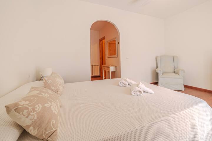 Cama de matrimonio del dormitorio 1 con cortinas rosadas.