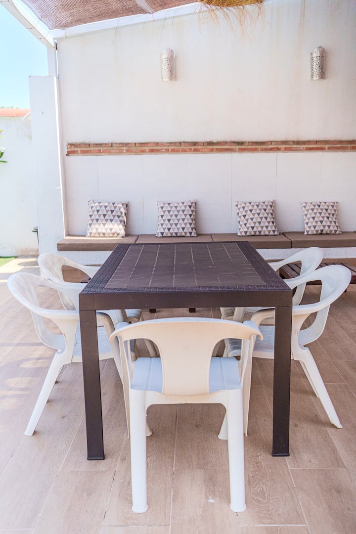 Comedor exterior con mesa y sillas junto a la piscina.