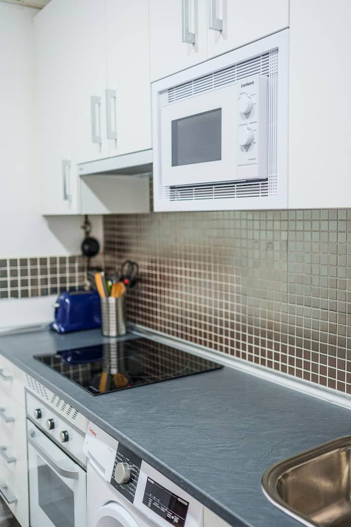 Cocina con azulejo verde y pequeños electrodomésticos.