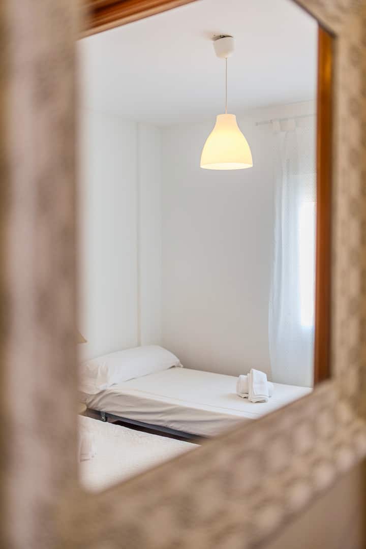 Dormitorio 2 luminoso con cortinas y ventana al jardín.