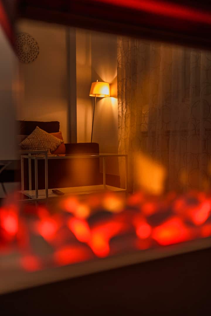 Rincón del salón con luz cálida junto a la chimenea.