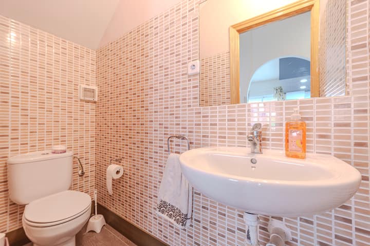 Aseo con lavabo y azulejo rosado.