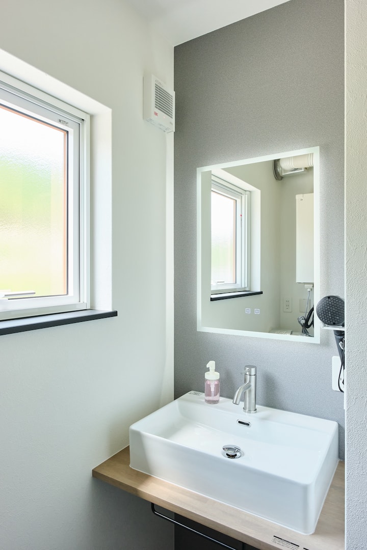 清潔感あふれる洗面化粧台は、窓から入る自然光で明るく、気持ちの良い朝を迎えられます。スタイリッシュなスクエア洗面ボウルと、周囲を照らすLEDライト付きミラーを完備。すっきりと身支度できる快適な空間です。