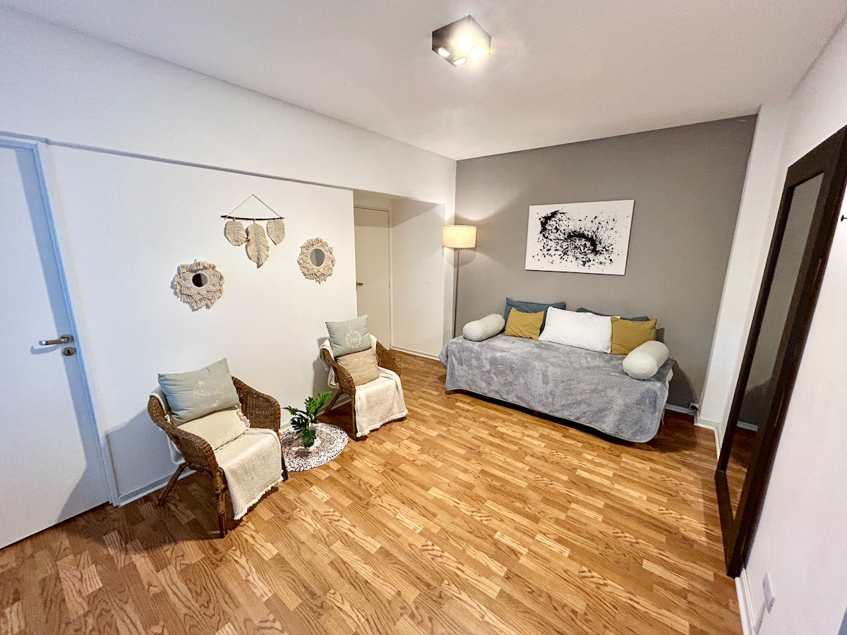 סלון/חדר אוכל עם ספה נפתחת, שולחן לשני אנשים וטלוויזיה.