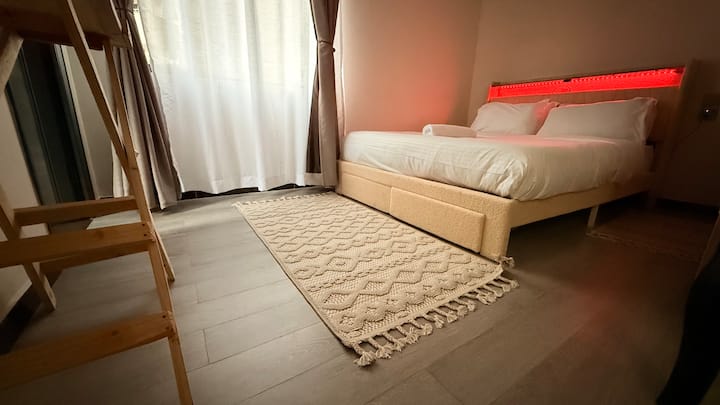 Útulná spálňa s moderným dizajnom, pohodlnou posteľou, tlmeným osvetlením a relaxačnou atmosférou. Tento príjemný priestor je ideálny pre cestovateľov, ktorí hľadajú pokojný oddych.