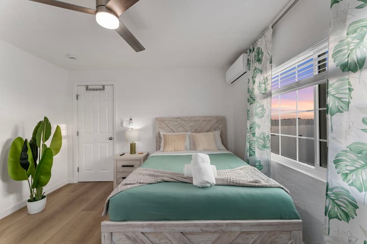 Оваа елегантна спална соба има рустикален дрвен кревет со зелена прекривка за кревет, беж и соодветна ноќна масичка. Огледален плакар, додека сиво биро со телевизор и монитор создава работен простор. Тавански вентилатор, клима уред и природна светлина обезбедуваат удобност.
