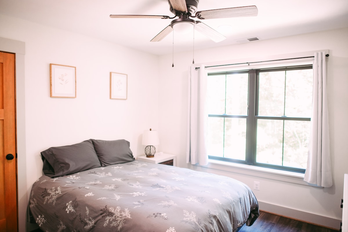 توفر غرفة النوم هذه سريرًا مريحًا بحجم كوين مع لحاف ناعم ومجموعة متنوعة من الوسائد الفخمة والصلبة. 