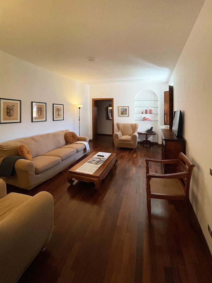 Amplio salón con un gusto clásico y acogedor, perfecto para relajarse después de un día explorando Lucca. Suelos de madera, muebles cómodos y detalles cuidados para que te sientas como en casa.
