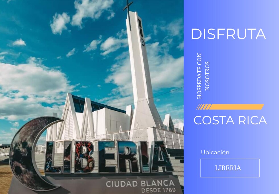A modern monument displaying the word 'Liberia' stands prominently in the foreground. Behind it, a striking white church with a tall cross reaches towards a blue sky, enhancing the historic and cultural significance of the location.