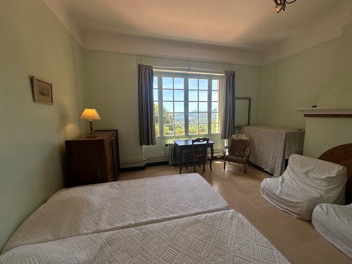 Une chambre accueillante avec grand lit et grandes fenêtres laissant entrer une belle lumière naturelle. Idéale pour des moments de repos en toute sérénité, avec vue sur la nature environnante et la mer.
