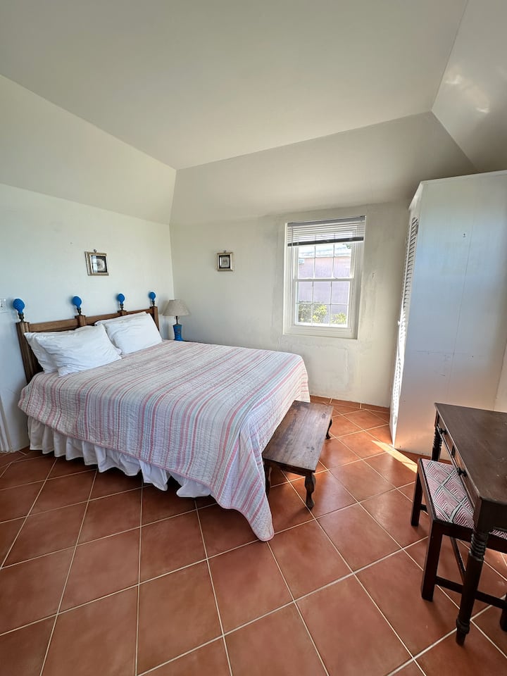 Cama tamaño queen con vistas despejadas de la costa sur de las Bermudas. Despierta con largas colas volando más allá de tu habitación y el sonido de las olas.  El baño está directamente cruzando el pasillo. 