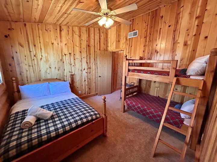 Charmante slaapkamer met een comfortabel tweepersoonsbed en stijlvolle stapelbedden. Warme houtaccenten en zachte verlichting maken dit de perfecte gezellige oase voor een goede nachtrust!