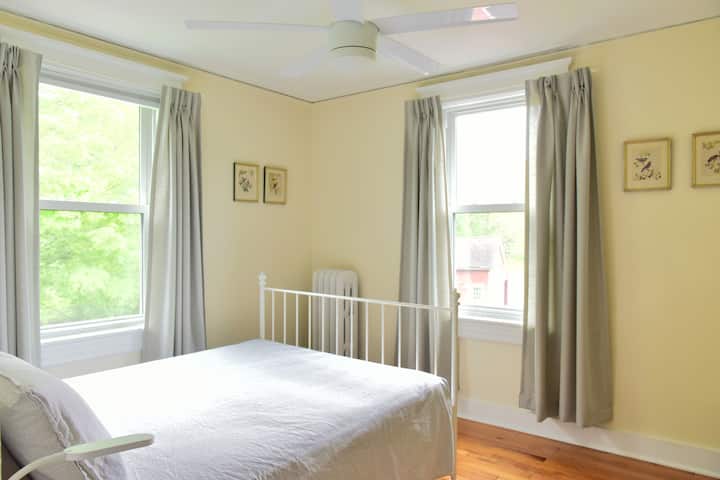 Este dormitorio en el segundo piso tiene vistas al patio trasero y a los campos.  Tiene una cama completa, ventilador de techo, lámpara de lectura junto a la cama y un armario con espacio para colgar y estantes.