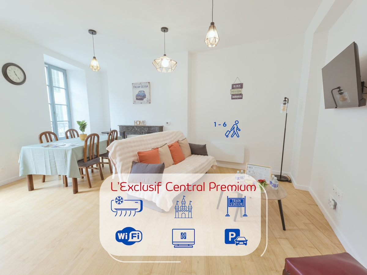 A bright living area showcases a comfortable sofa bed, designed to accommodate guests. A dining table with wooden chairs provides space for meals. Natural light enters through a large window, enhancing the neutral-toned walls. A television is mounted on the opposite wall.