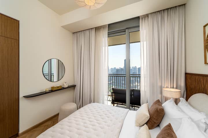 Chumba cha kulala cha kimtindo kilicho na kitanda cha starehe, fanicha za kisasa na madirisha ya sakafu hadi dari yanayotoa mandhari ya kupendeza ya jiji, mchana na usiku.