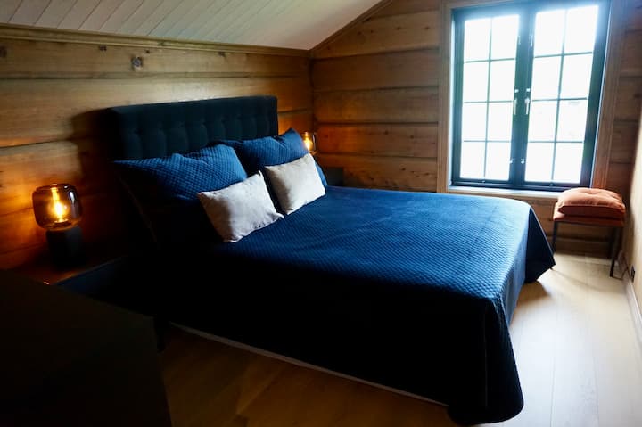 Bedroom 1: Main bedroom on the upper floor with a soft, elegant atmosphere, plush bedding, and large windows offering a beautiful mountain view - wake up to nature at its finest!