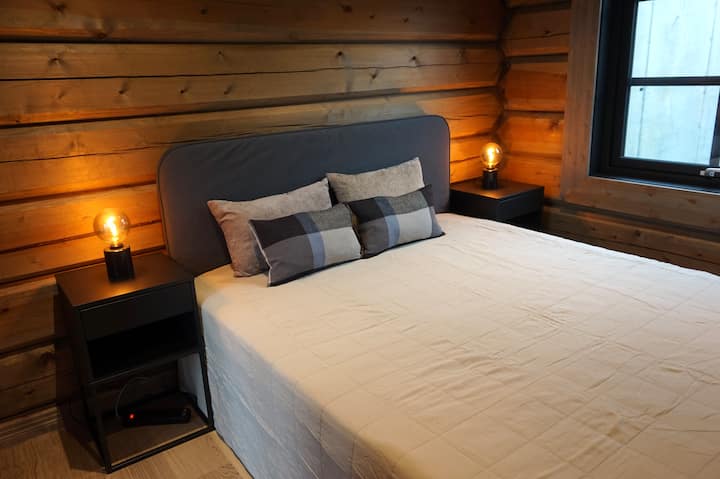 Bedroom 4: Warm and inviting bedroom with soft lighting, natural wood walls, and a large comfortable bed - perfect for unwinding after a day in the mountains.