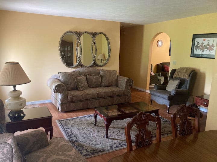 La sala de estar principal ofrece un encanto sureño clásico con asientos lujosos, espejos vintage y espacios acogedores perfectos para conversar, leer o relajarse después de un largo día.