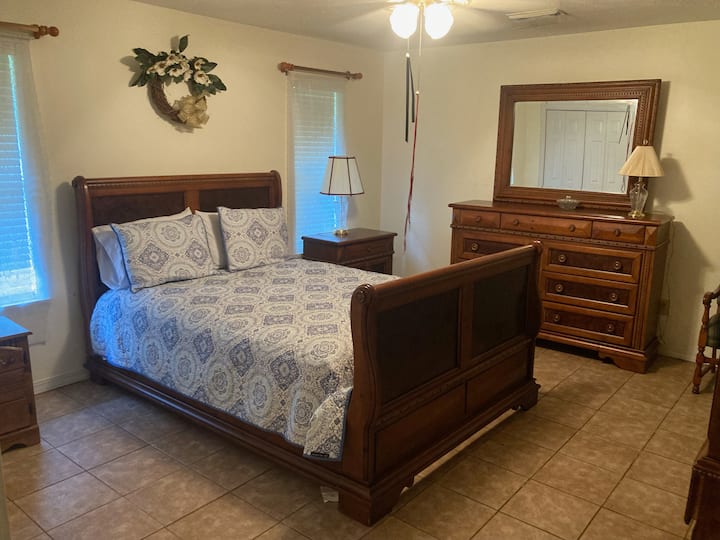 El dormitorio principal cuenta con una cama de trineo bellamente tallada, muebles de madera clásicos y luz natural suave, que ofrece un espacio acogedor y tranquilo para relajarse.