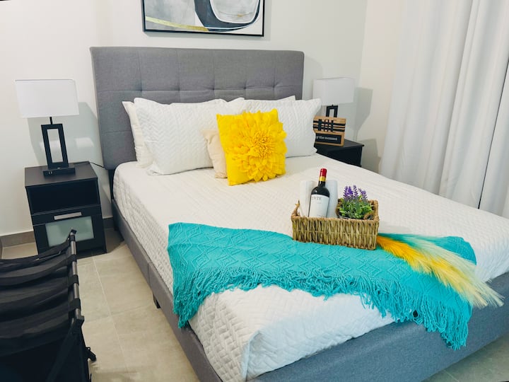 U ovoj spavaćoj sobi nalazi se bračni krevet sa sivim uzglavljem, bijelom posteljinom sa žutim i plavozelenim detaljima i crnim noćnim ormarićima. Soba je uređena u suvremenom stilu s apstraktnom umjetnošću, ima privatni balkon i pruža pogled na bazen i krajolik.