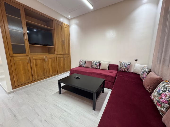  صالة تلفزيون مع مقعد مريح وأثاث خشبي صلب وبلاط بتأثير الباركيه. مثالية للاسترخاء أمام فيلم أو الدردشة في مجموعات صغيرة أو الاستمتاع بلحظة هادئة في الداخل.