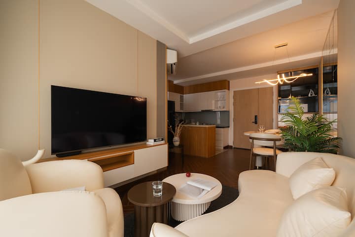 Შეაბიჯეთ მე-20 სართულზე მდებარე ნათელ და ელეგანტურ მისაღებ ოთახში, საიდანაც თვალწარმტაცი ხედები იშლება. Იატაკიდან ჭერამდე დიდი ფანჯრები საცხოვრებელს დღისით ბუნებრივი სინათლით ავსებს, ღამით კი ქალაქის ბრჭყვიალა ჰორიზონტს წარმოაჩენს.