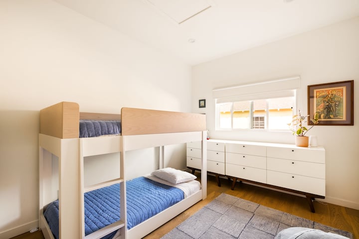 Модерна стая с двуетажни легла с плюшени матраци Avocado, затъмняващи завеси за спокоен сън и просторен скрин с 9 чекмеджета плюс пълен гардероб. Топлите дървени подове, мекият килим и винтидж декорът създават приветливо място за отдих за семейства или приятели.